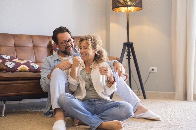 adult young couple man and woman sitting on the floor at home enjoying in leisure indoor activity together love and relationship middle age people having relax time in living room